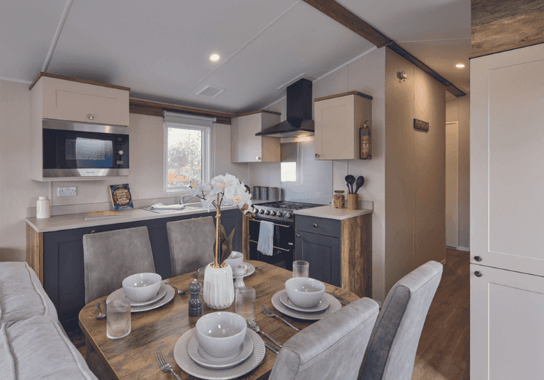 Modern holiday lodge kitchen and dining area with navy and cream units, place settings for four