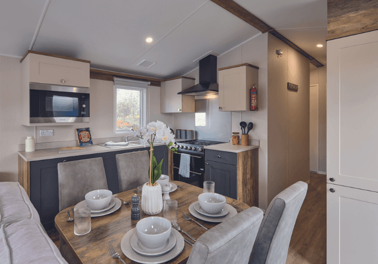 Modern holiday lodge kitchen and dining area with navy and cream units, place settings for four
