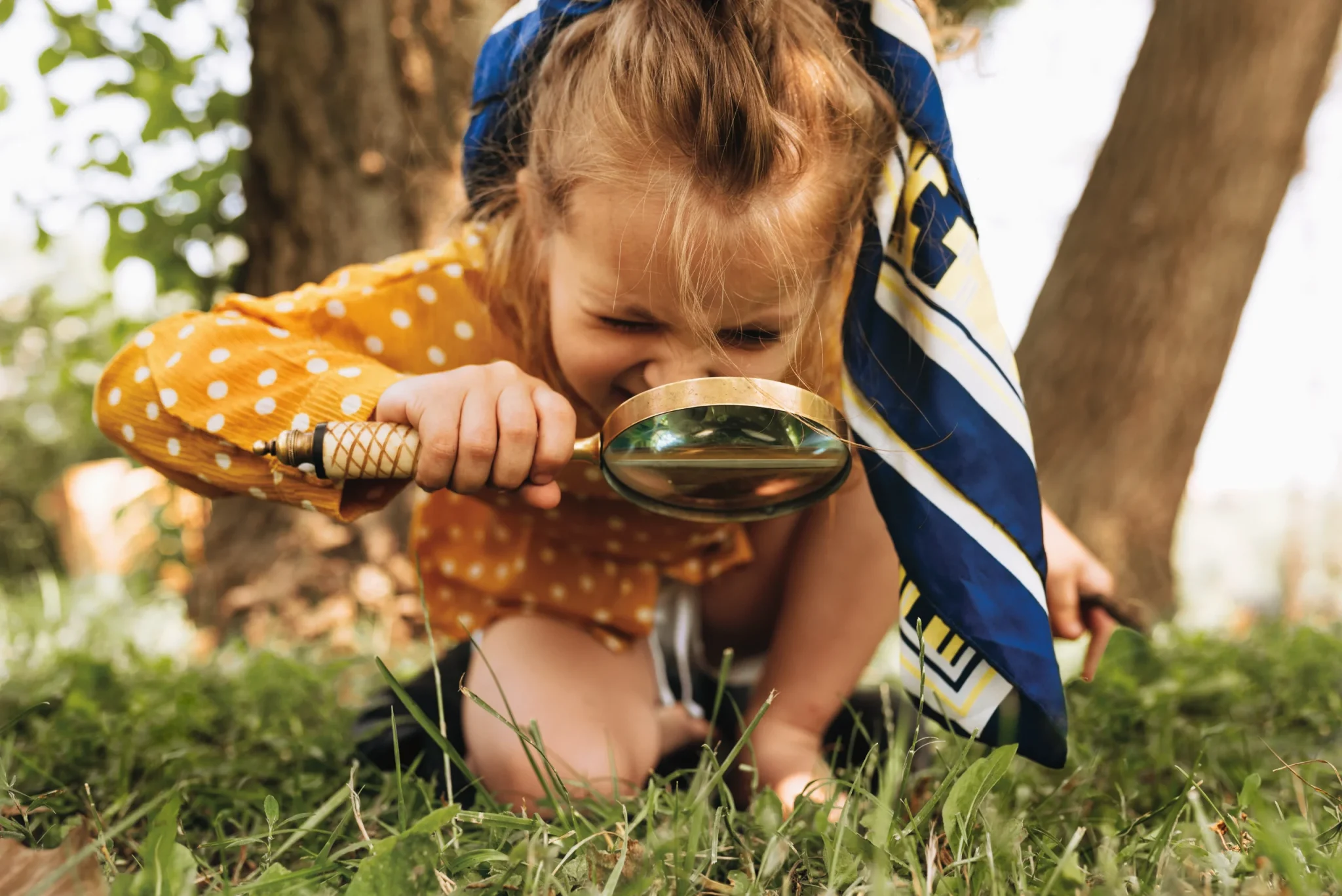 Young girl exploring nature with a magnifying glass during an outdoor adventure on Cheshire holidays Warrington.