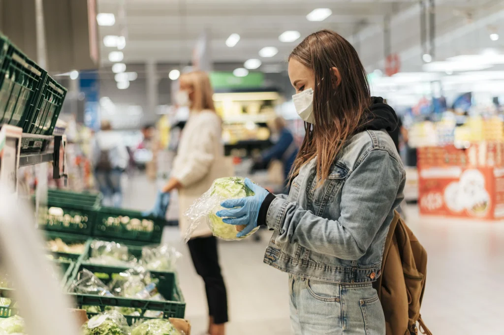 Woman wearing a mask selecting lettuce in a supermarket, highlighting safe and local shopping as part of family days out Rother Valley.